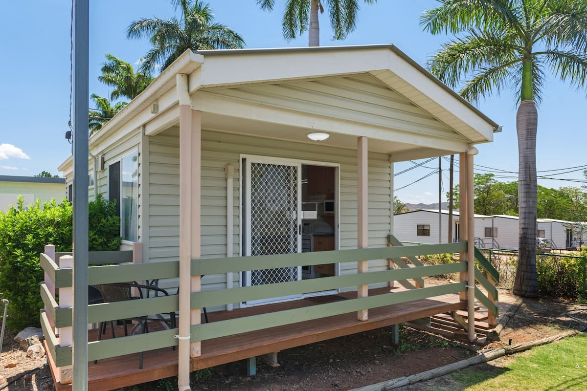 A small, single-story mobile home with a porch and a covered outdoor area.