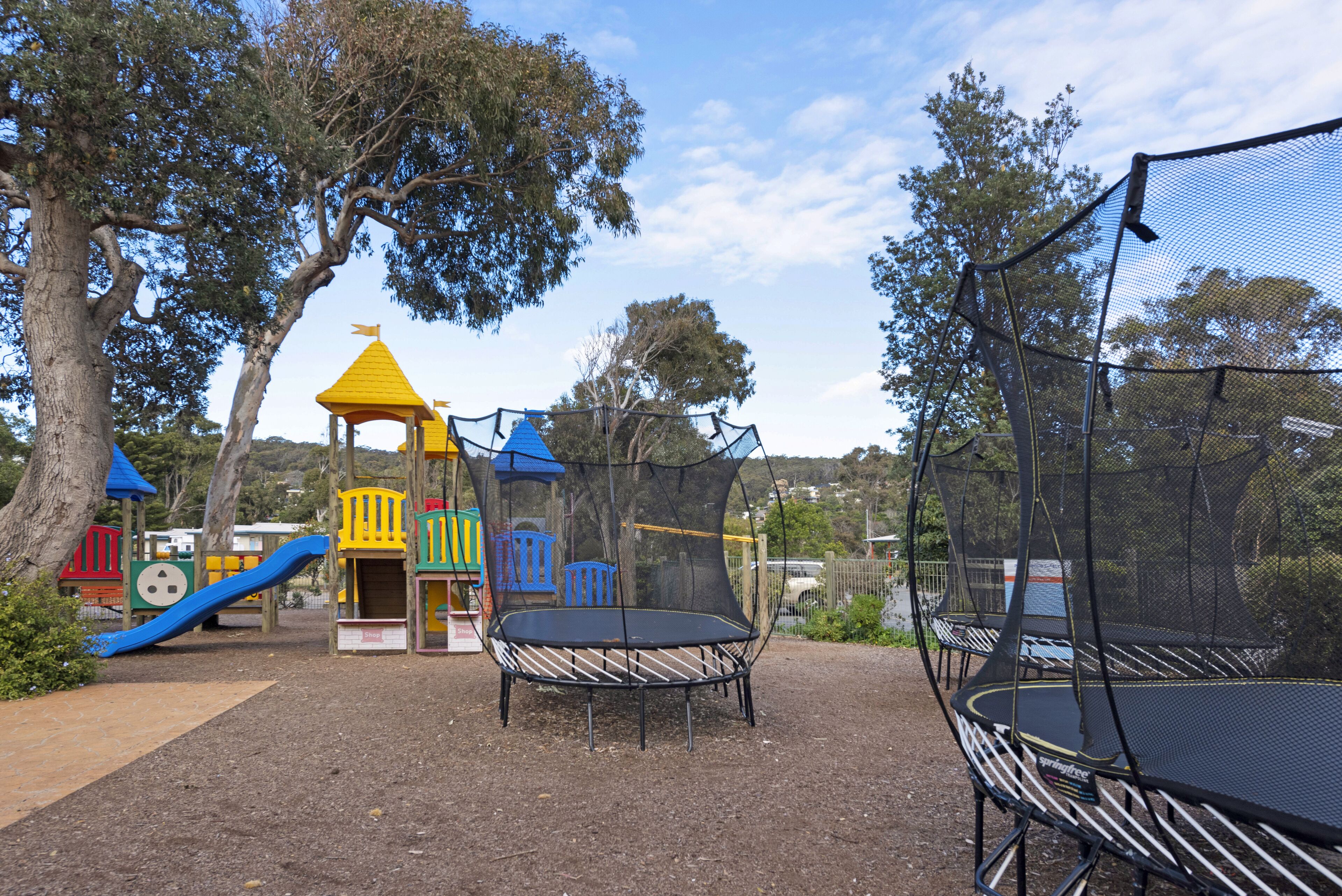A playground with a slide, climbing structures, and a trampoline area.