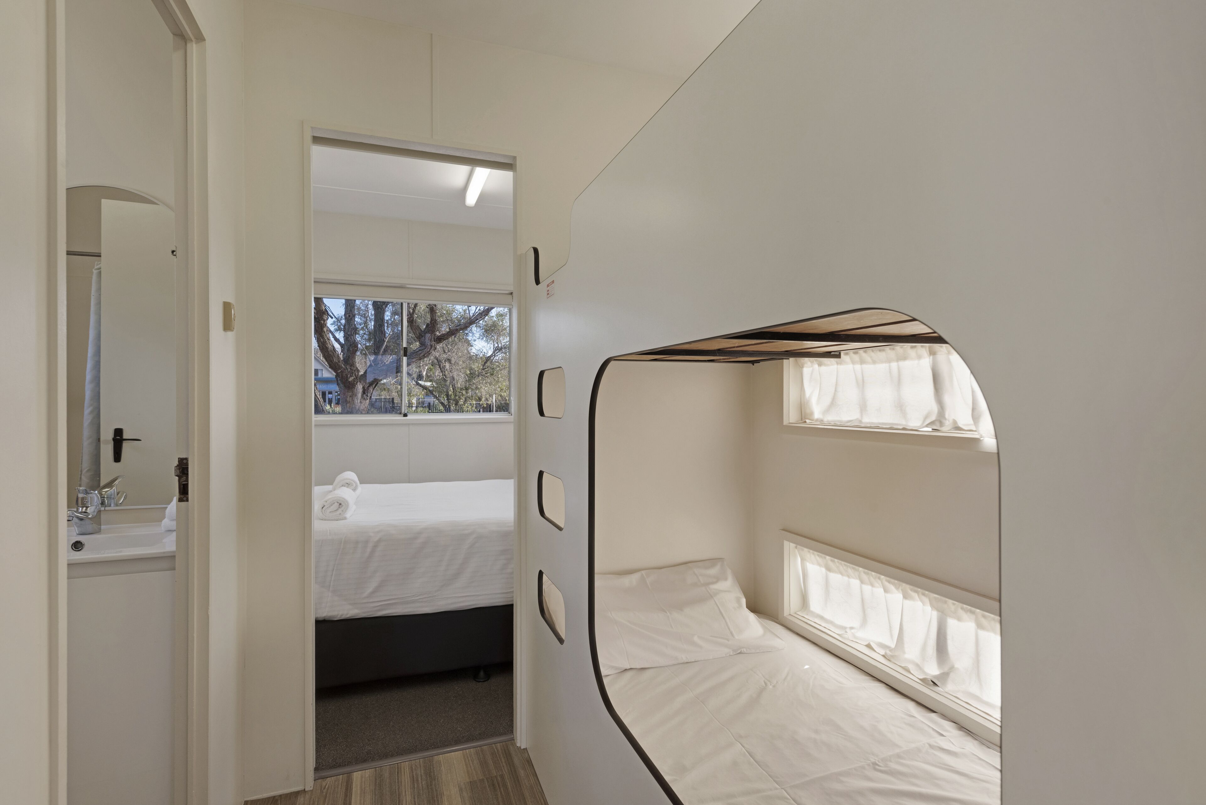 Ein kleines Zimmer mit Bett, Fenster und Spiegel.