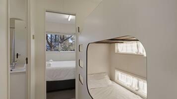 Ein kleines Zimmer mit Bett, Fenster und Spiegel.