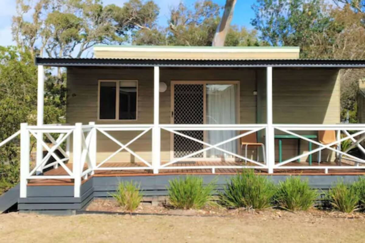 A single-story house with a porch, a sliding door, and a small outdoor seating area.