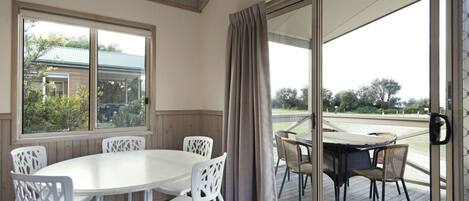 A room with a sliding glass door leading to an outdoor patio. Inside, there is a round table with white chairs.