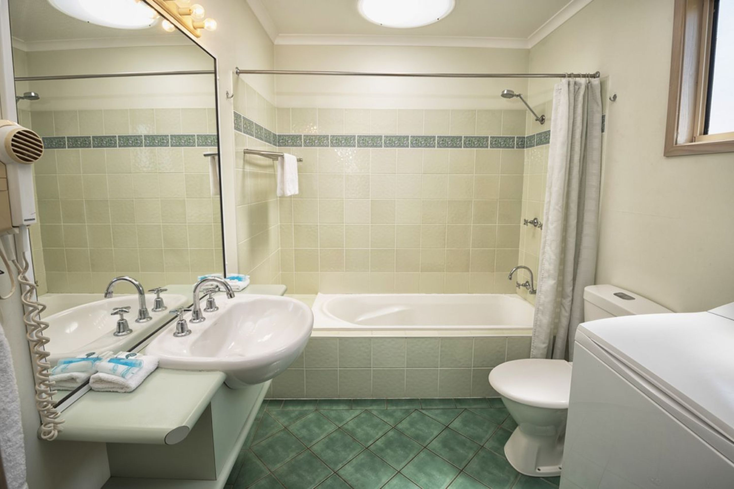 Un baño con ducha, inodoro, lavamanos y espejo.