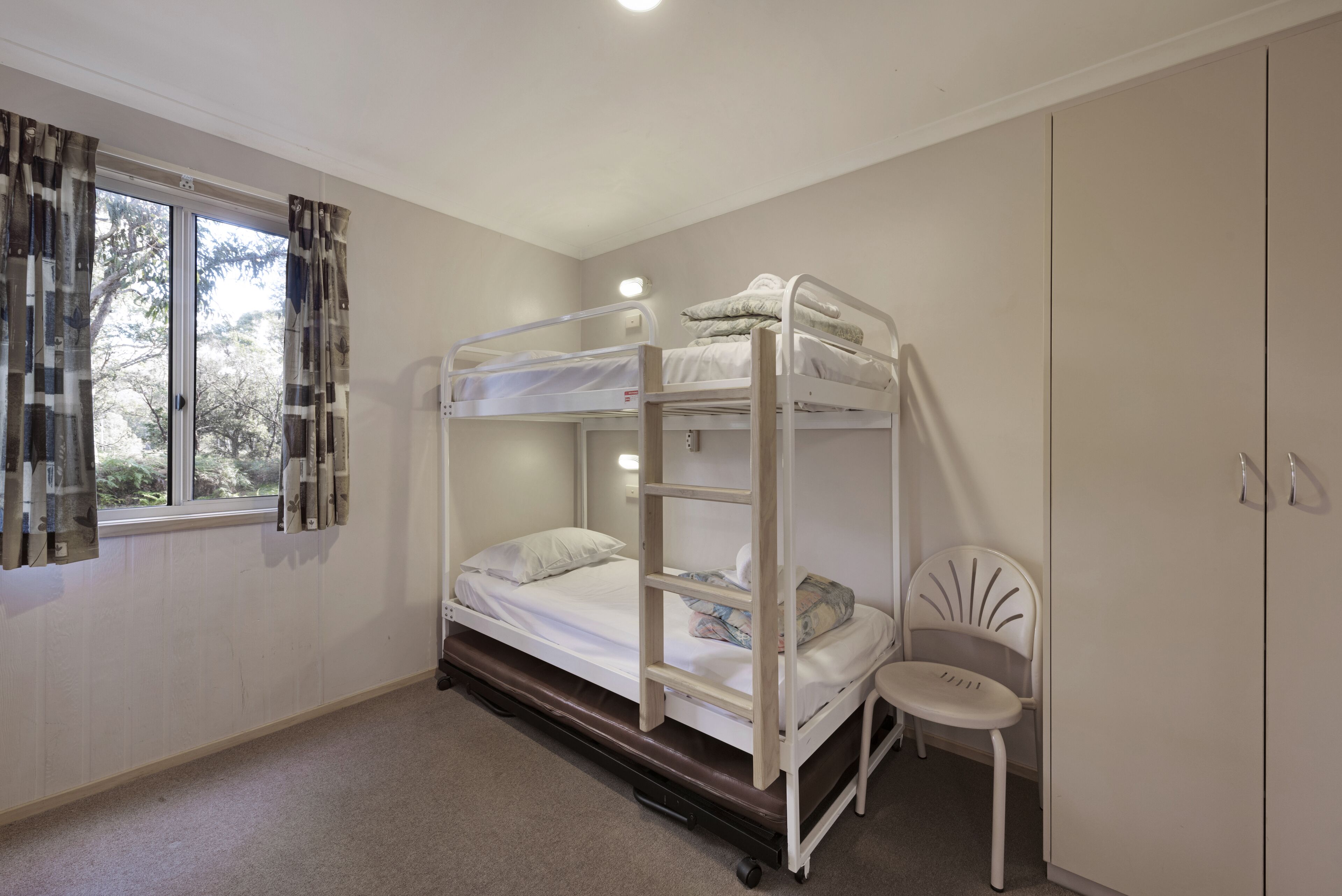 Habitación con literas, una ventana, una silla y un armario.