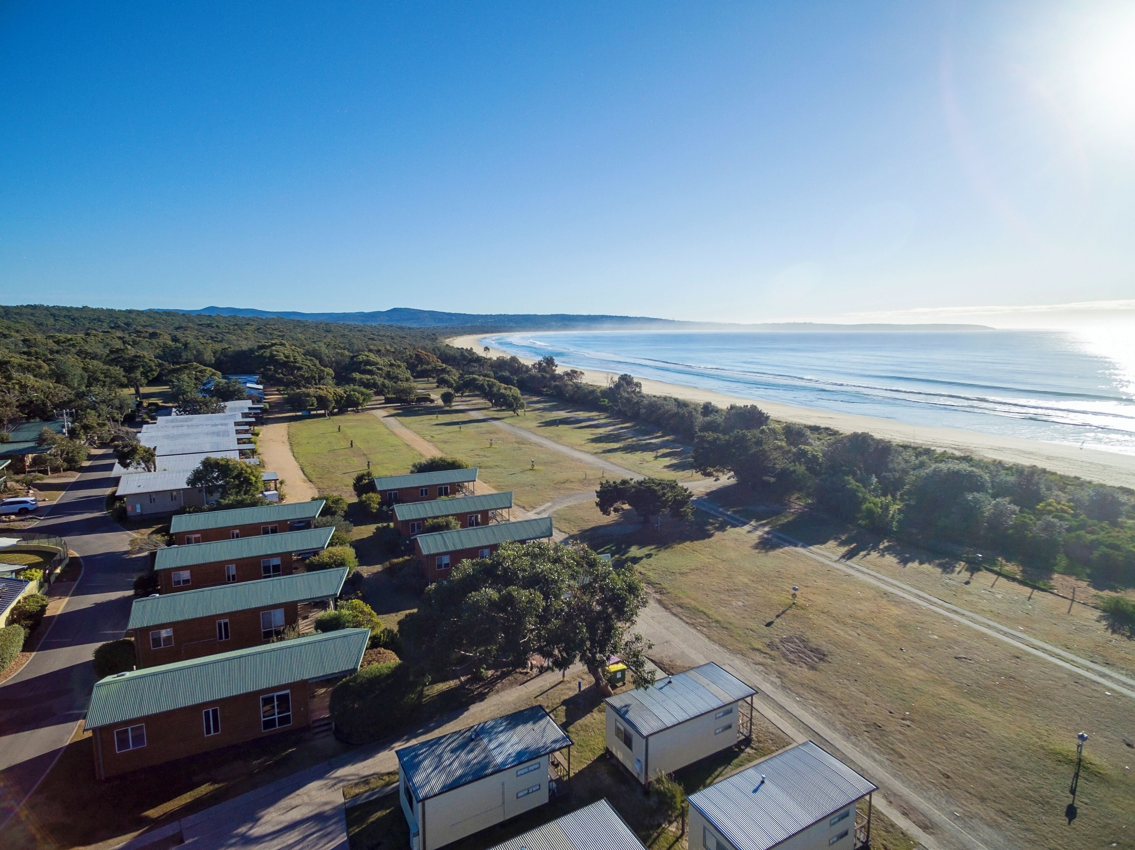 A coastal property with multiple buildings, a beach, and a clear view of the ocean.