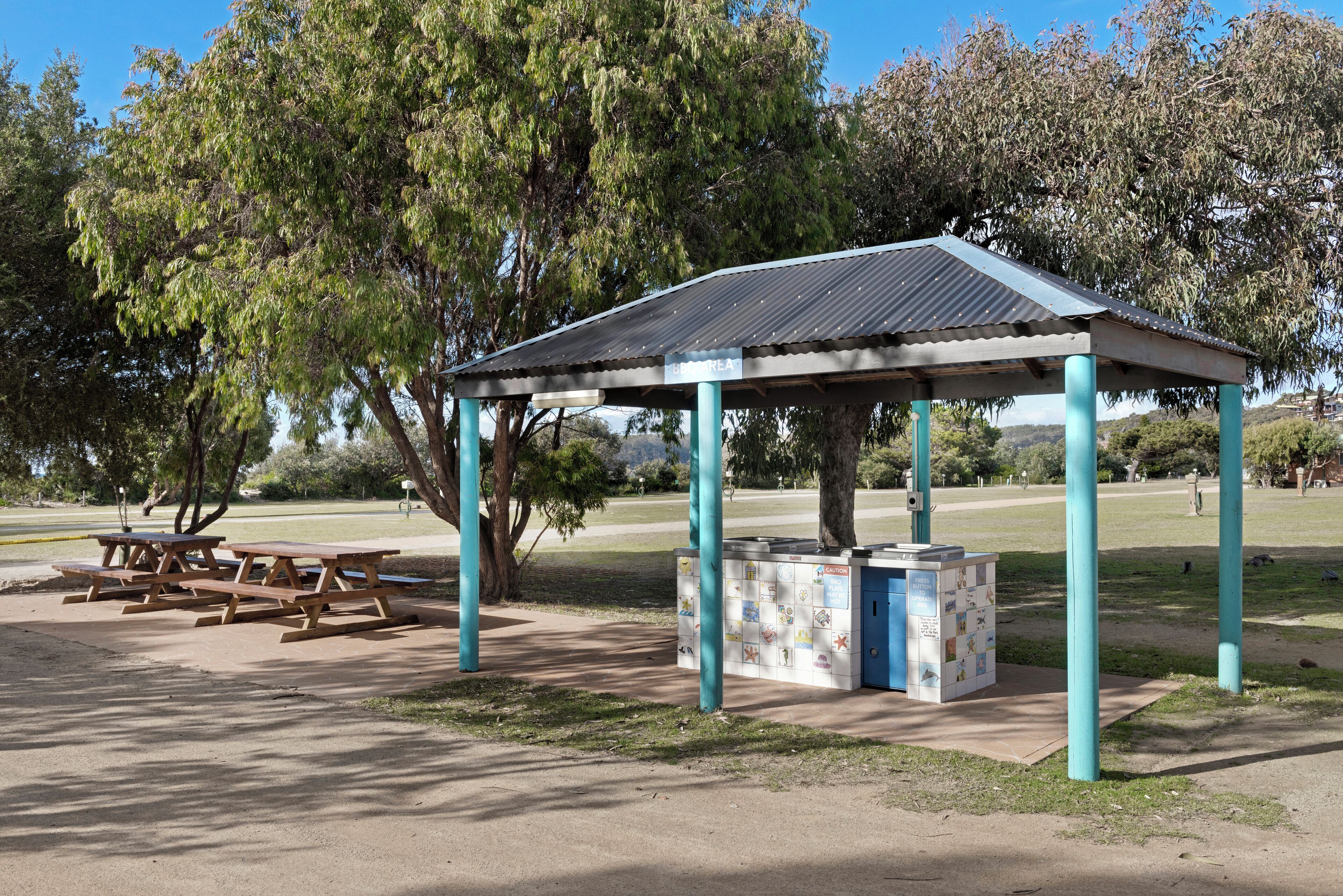 Un pavillon de parc avec des tables de pique-nique et un petit kiosque.
