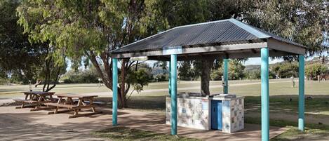 Un pavillon de parc avec des tables de pique-nique et un petit kiosque.