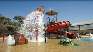 Parque acuático con tobogán de agua, zona de juegos con agua y estructura de juegos.