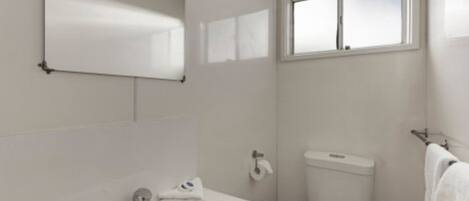 A small, clean bathroom with a white sink, toilet, and window.