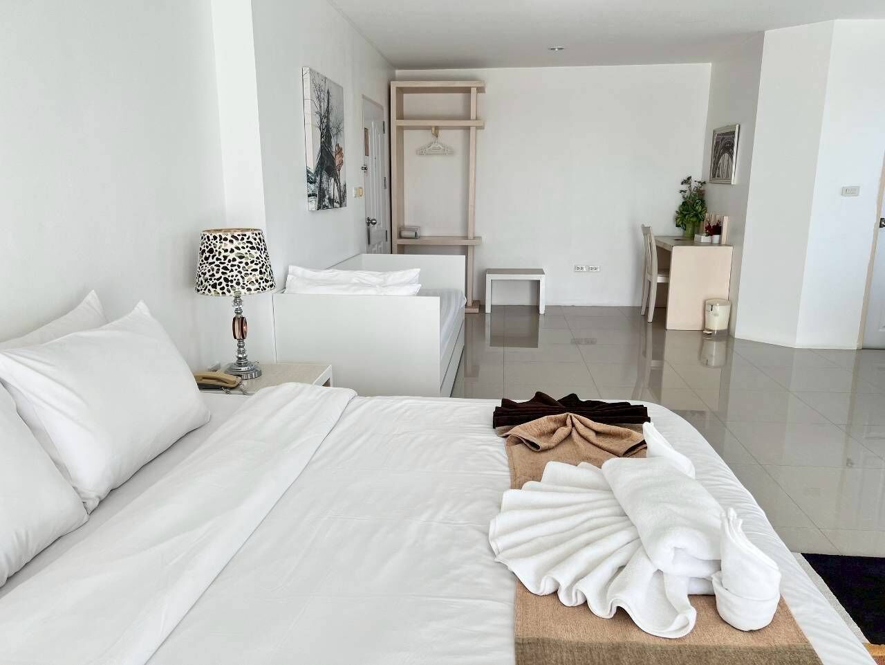 Una habitación de hotel con una cama, una mesita de noche, una lámpara y un pequeño escritorio con una silla.