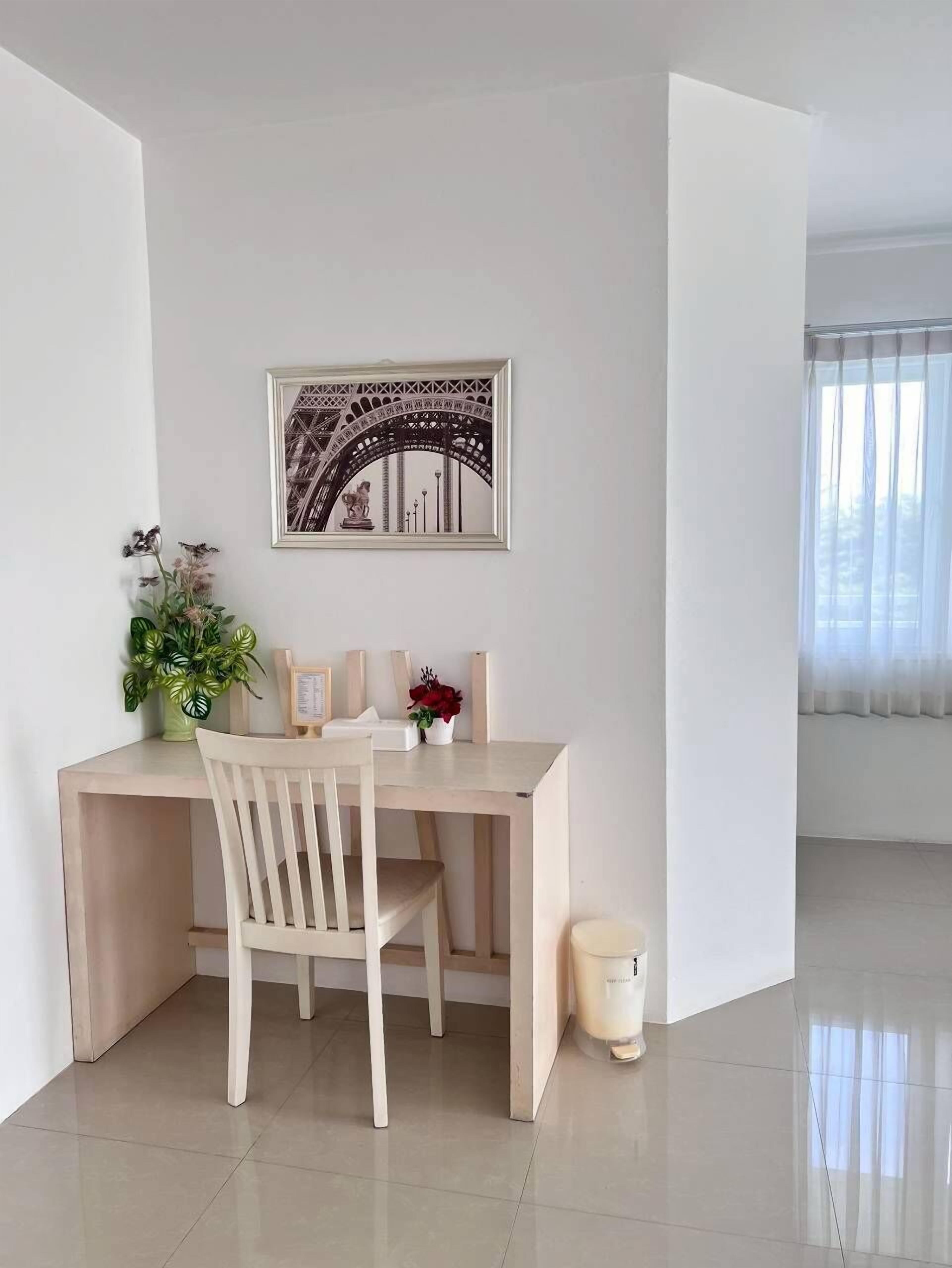 Habitación minimalista con escritorio, silla y un cuadro con la Torre Eiffel.