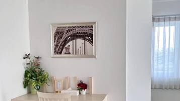Habitación minimalista con escritorio, silla y un cuadro con la Torre Eiffel.