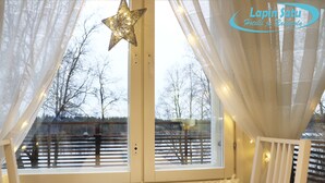 Ein Zimmer mit großem Fenster, einer Sterne-Dekoration und Blick auf Bäume sowie einen Zaun.