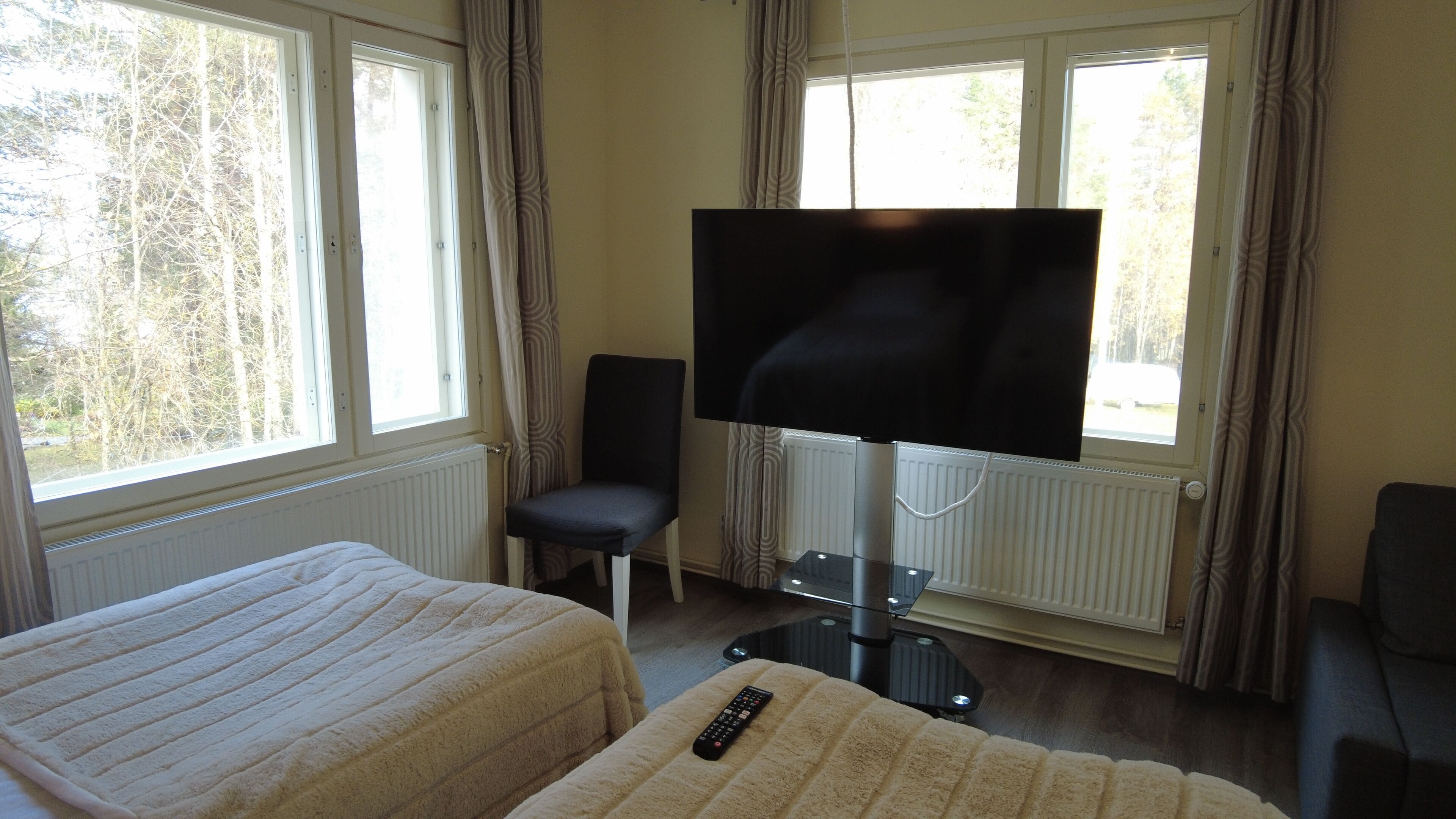 A hotel room with two beds, a TV, and a window with curtains.