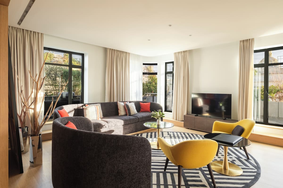 A modern living room with a sofa, yellow chairs, a coffee table, and a TV.