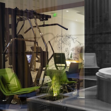 A gym area with exercise equipment, a green chair, and a hot tub.
