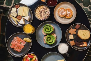 A variety of breakfast items including smoked salmon, avocado toast, pancakes, and assorted pastries on a table.
