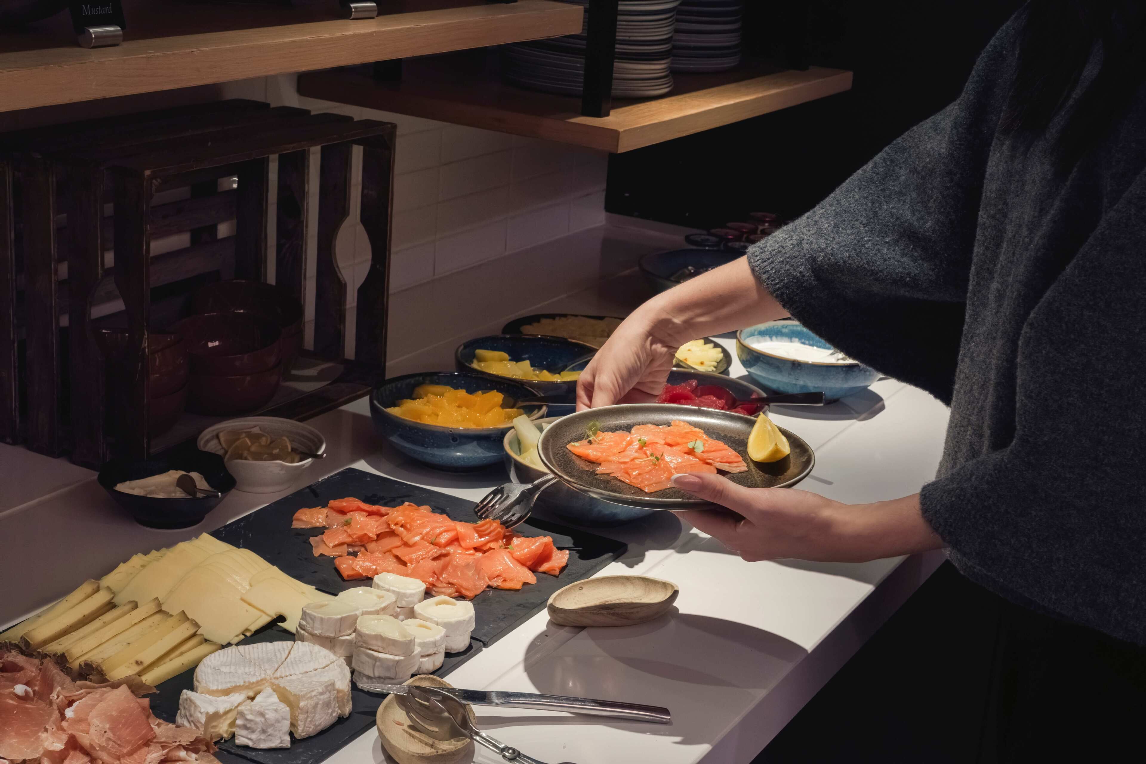 A buffet table with various cheeses, meats, and fruits.