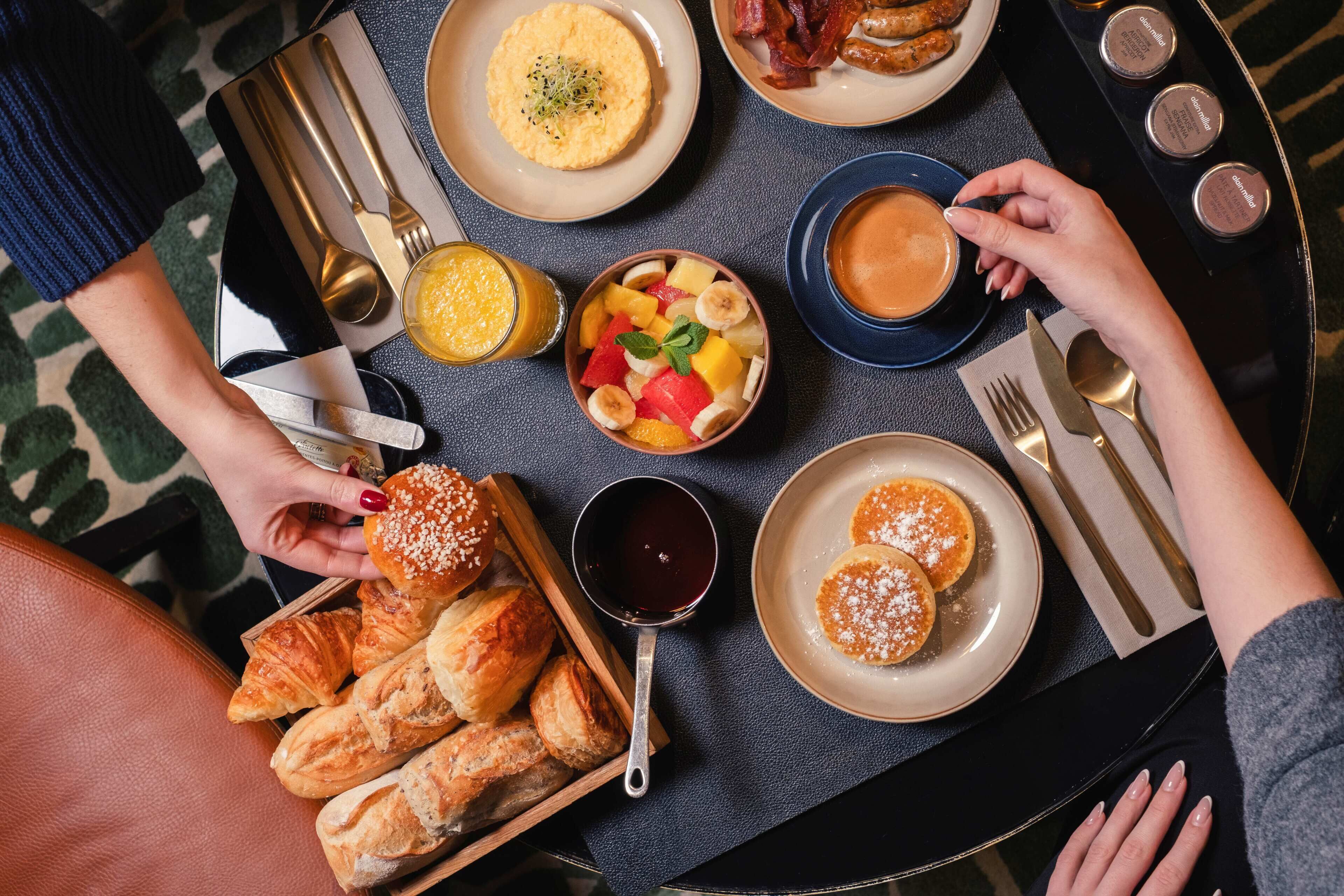 Ein Frühstücksbuffet mit Croissants, Obst, Pfannkuchen und Kaffee.