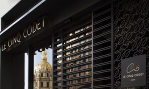 A building facade with the sign "LE CINQ CODET PARIS" and a view of a classical building with a dome.