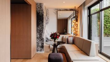 Ein modernes Interieur mit Holzboden, einer strukturierten Wand in Schwarz-Weiß, einem runden Tisch mit Blumenvase, einer Couch mit Kissen und einem großen Fenster mit Blick auf Grünflächen.
