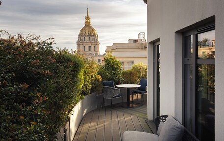 A wooden deck with outdoor seating, a view of a historic building with a dome, and a modern building in the background.