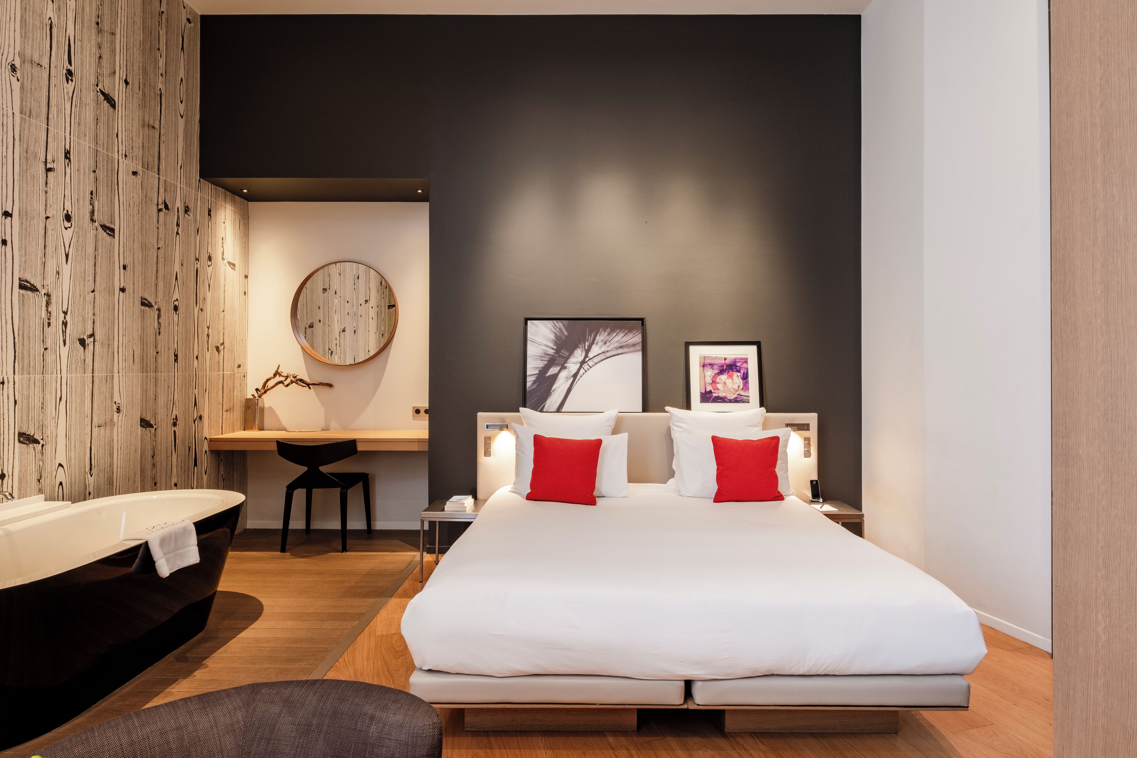 Une chambre moderne avec un grand lit, des tables de chevet, un bureau et une baignoire.