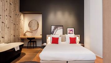 Une chambre moderne avec un grand lit, des tables de chevet, un bureau et une baignoire.