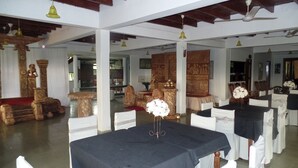 Een balzaal met gedekte tafels voor een formeel evenement, met witte stoelen en zwarte tafelkleden.