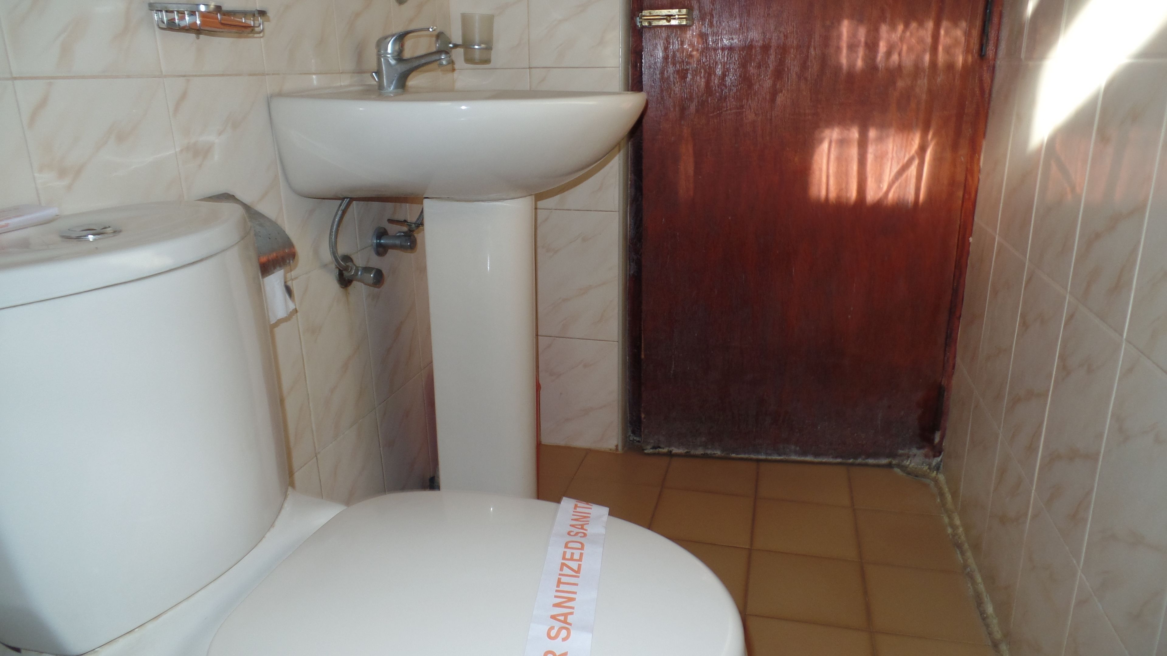 A bathroom with a toilet, sink, and a door.