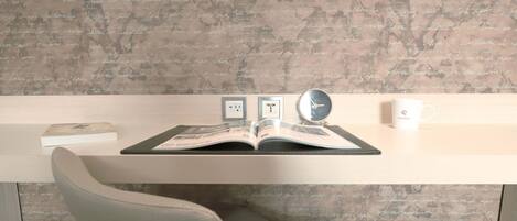 A room with a wooden desk, a book, a clock, and a mug.