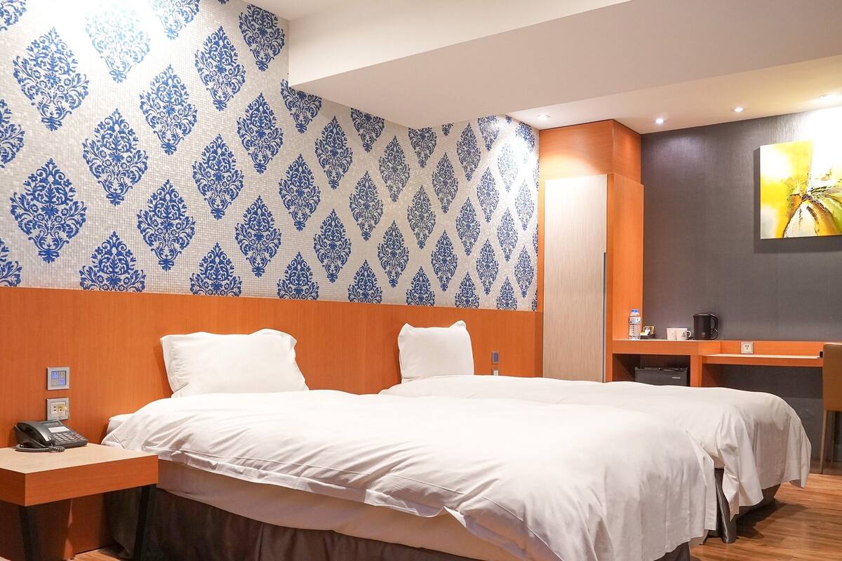 A hotel room with a large bed, a desk with a phone, and a small table with a coffee cup.