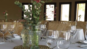 Una mesa de comedor vestida con mantel blanco, platos, cubiertos y copas de cristal.