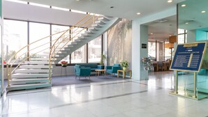Un hall d’hôtel moderne avec un escalier en colimaçon, un espace salon et un panneau indiquant l’emplacement du centre de conférences.