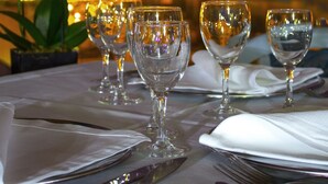 Une table dressée pour le dîner, avec des verres à vin et des couverts, une orchidée blanche, et en arrière-plan, une vue sur les lumières de la ville.