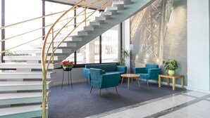 Un hall d’entrée moderne avec un escalier, un espace salon et une grande fenêtre donnant sur un pont.