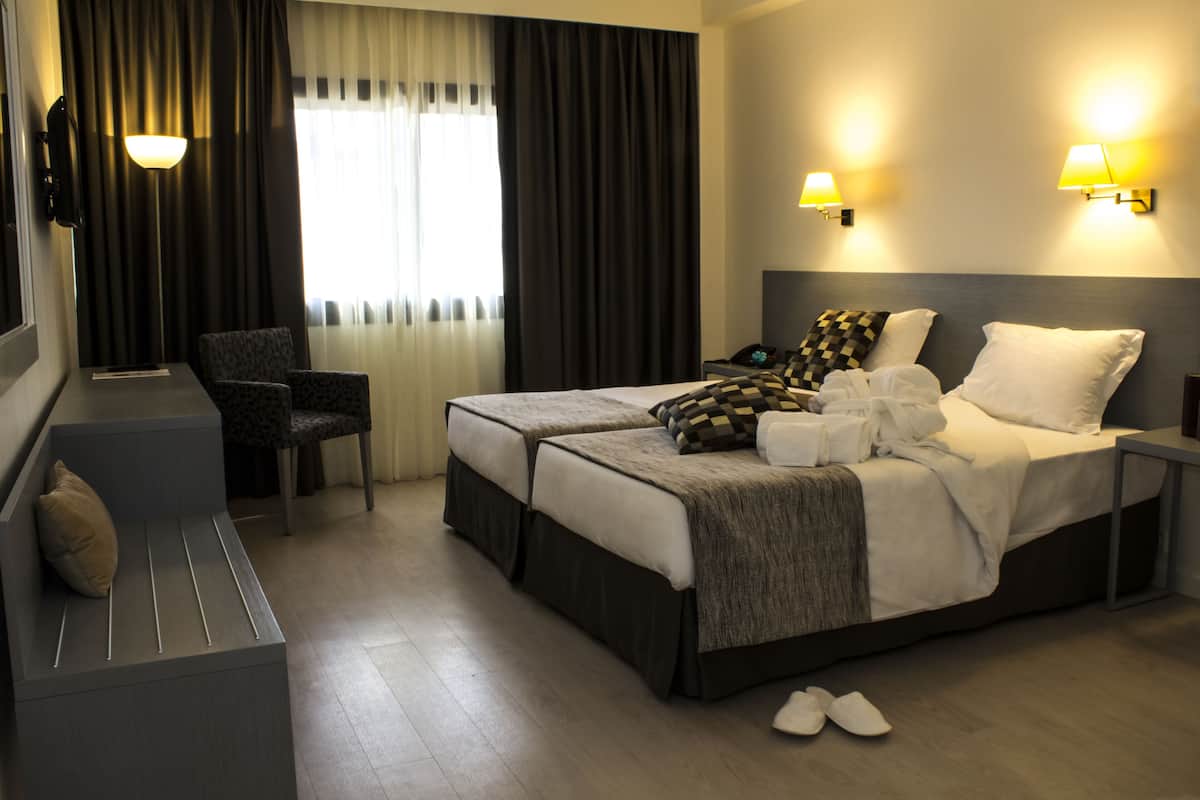 A hotel room with a large bed, a chair, a desk, and a lamp.