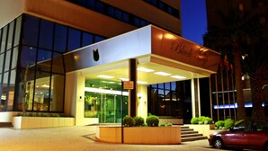 L’entrée d’un hôtel au design moderne, avec une façade en verre et une enseigne indiquant qu’il s’agit de l’hôtel Black and White.