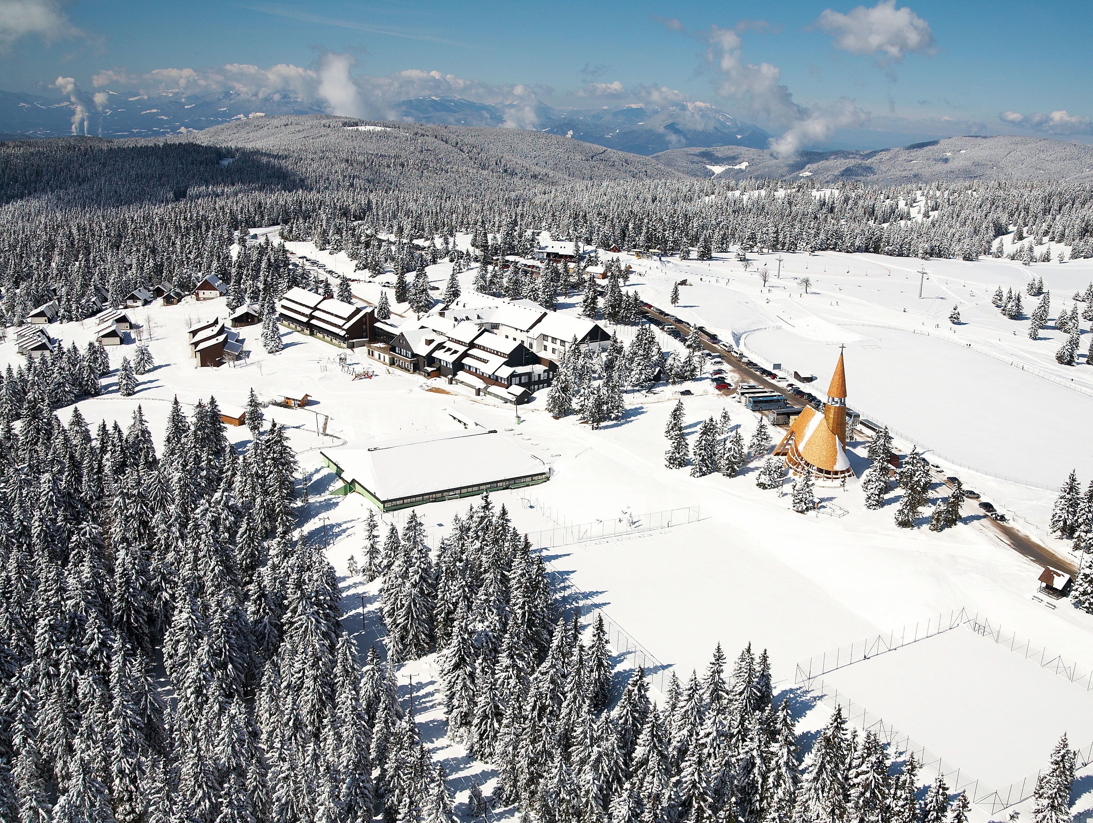 A snow-covered village with buildings, a church, and a ski slope.