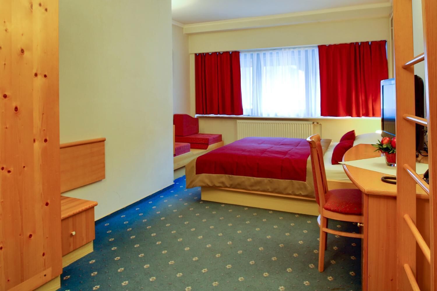 A compact room with a bed, a desk, and a chair.