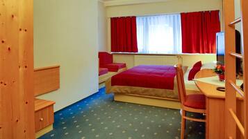 A compact room with a bed, a desk, and a chair.