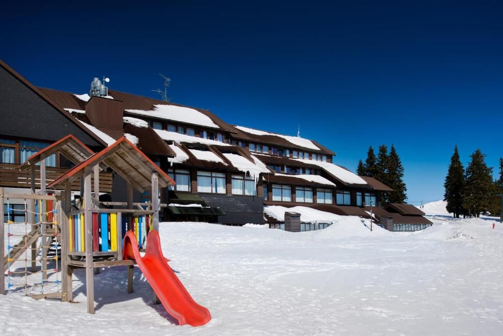 A ski resort with a red slide, wooden buildings, and snow-covered roofs.