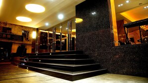 A modern hotel lobby with a marble staircase, glass doors, and a large mirror reflecting the interior. - Talmud Hotel Taichung (Taichung)