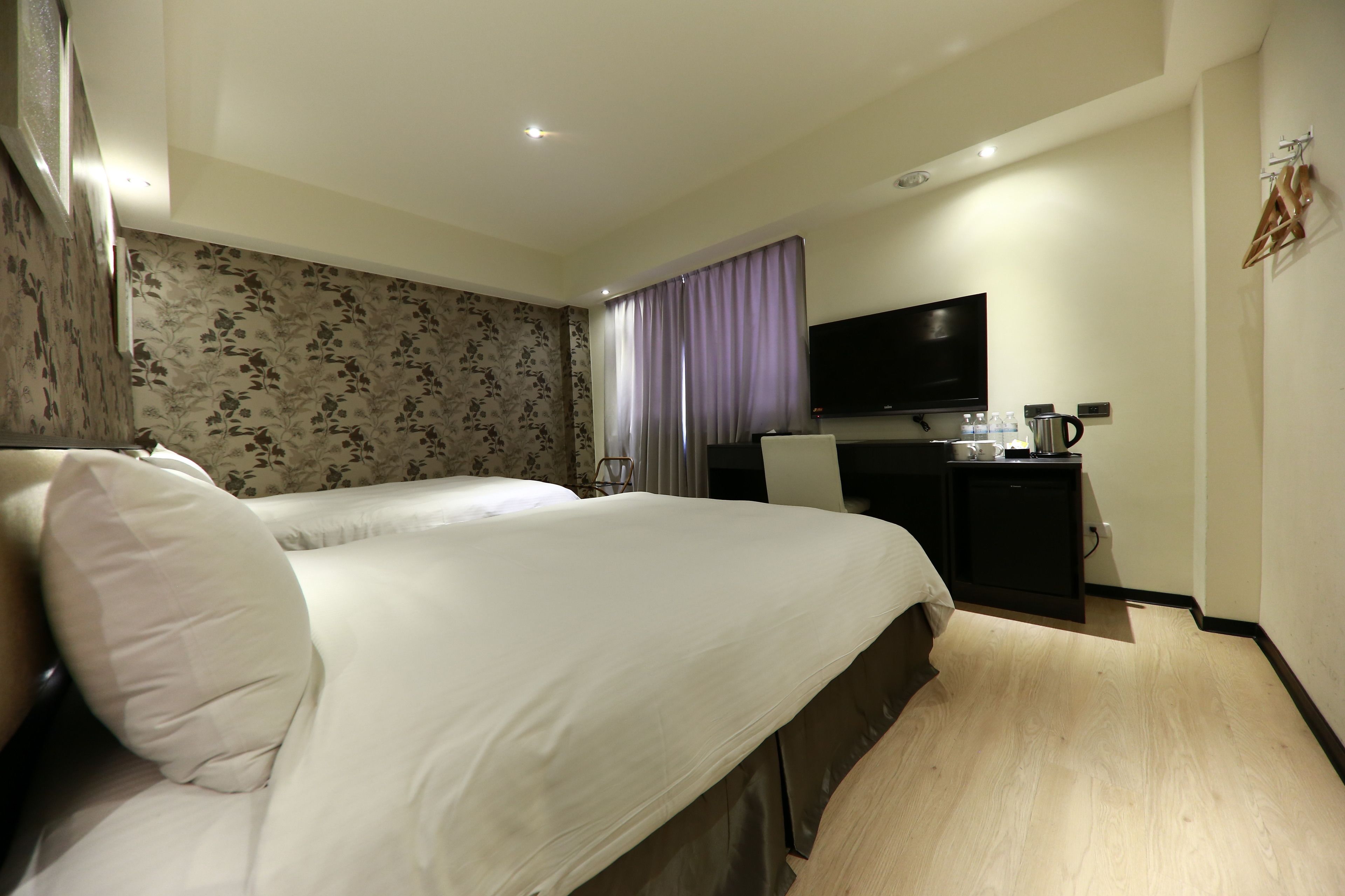 A hotel room with a bed, a desk, a television, and a coffee machine.