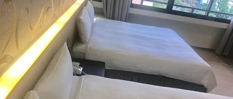 A hotel room with two beds, a headboard, and a window with a city view.