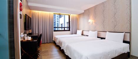 Habitación de hotel con dos camas, un escritorio con silla, televisión y ventana con cortinas.