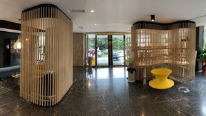 A modern lobby with a marble floor, a yellow table, and wooden partitions. - Talmud Hotel Taichung (Taichung)