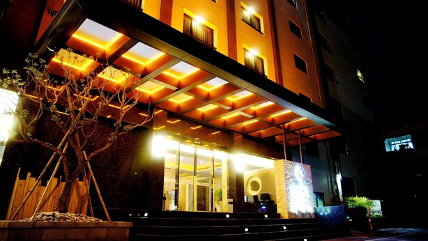 A hotel entrance with a covered walkway, glass doors, and a potted tree. - Talmud Hotel Taichung (Taichung)