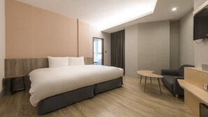 A modern hotel room with a large bed, a desk, a chair, and a TV mounted on the wall. - Sparrow Hotel (Taichung)