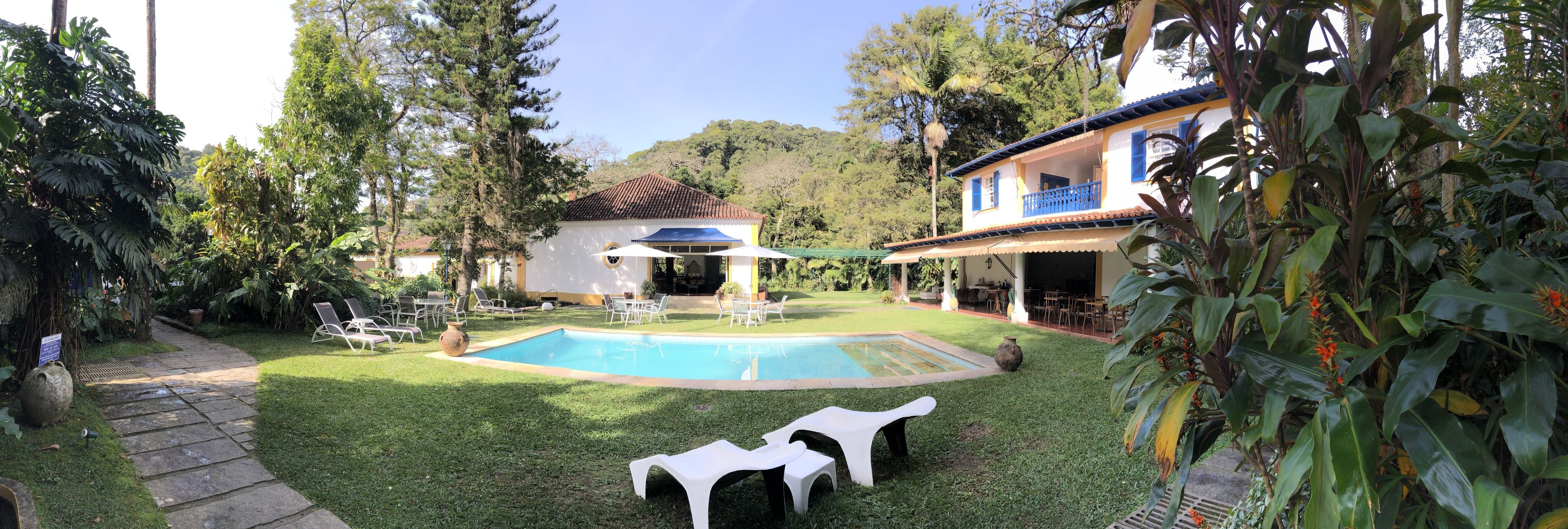 A pool area with a small house, outdoor seating, and lush greenery.